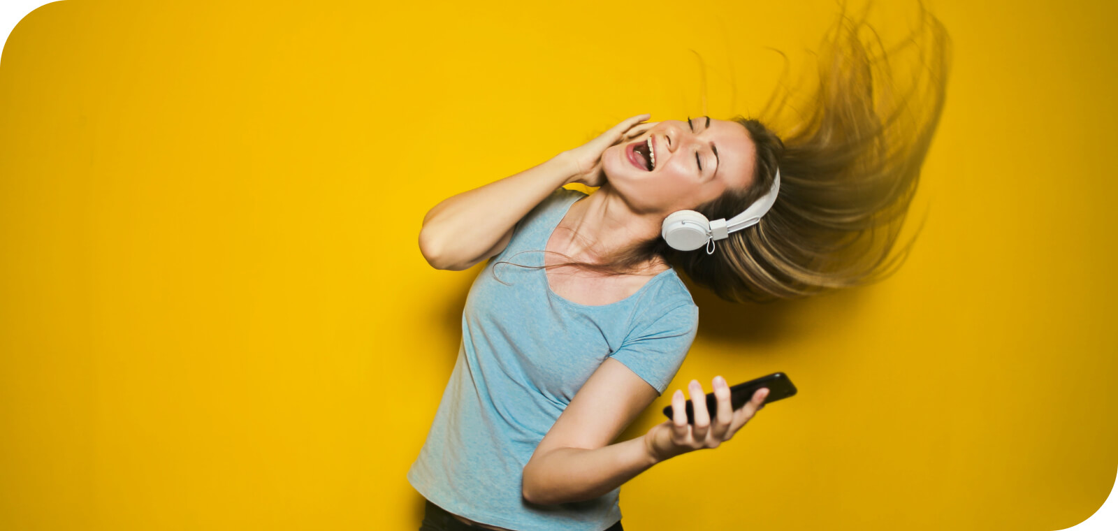 女性がスマートフォンとワイヤレスヘッドフォンで音楽を楽しんでいる様子